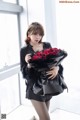 A woman holding a bunch of red roses in her hands.