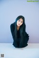 A woman with long black hair sitting on a white surface.