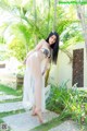 A woman in a sheer white dress posing for the camera.