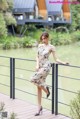 A woman in a dress standing on a bridge.