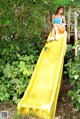 A young woman is sitting on a yellow slide.